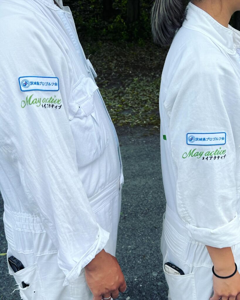 Home 「茨城県プロゴルフ会」と「May active」のロゴが入った白い作業服を着用した二人の人物。